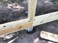 an unfinished wooden fence post with nails sticking out of the ground next to some wood planks