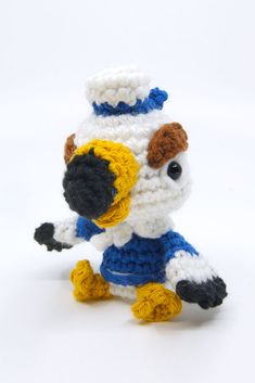 a crocheted stuffed animal that is wearing a blue and white outfit with yellow feet