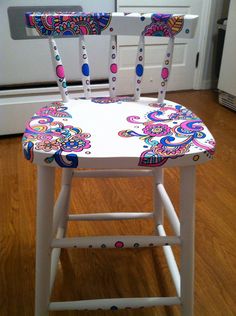 a white wooden chair with colorful designs on it's seat and backrests