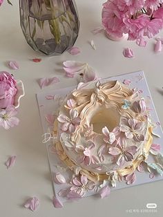 the cake is decorated with pink flowers and leaves on the table next to some vases