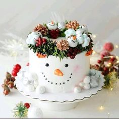 a cake decorated with flowers and snowmen on top of a white plate next to christmas decorations