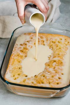 someone pouring sauce into a casserole in a glass dish