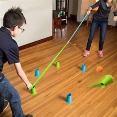 two children playing with plastic cups and poles on the floor in front of an open living room door