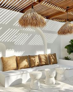 an outdoor seating area with straw umbrellas on the roof, and white tiles flooring