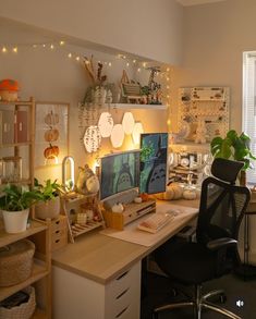 a desk with a computer on top of it next to a plant and potted plants