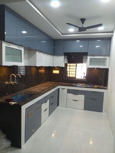 a kitchen with white and grey cabinets and black counter tops, along with a ceiling fan