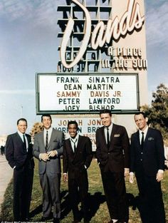 four men standing in front of the sands sign