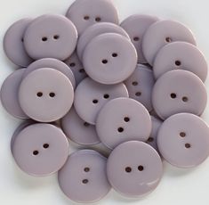 a pile of lavender colored buttons sitting on top of a white countertop next to each other