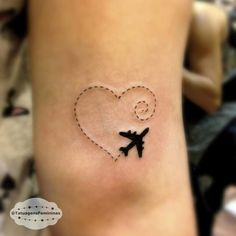 a small tattoo on the arm of a woman with an airplane in the shape of a heart