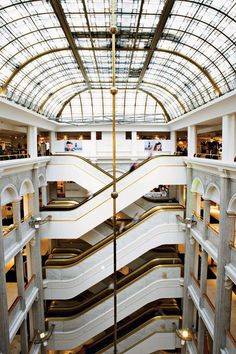 the interior of a shopping mall with an escalator and glass roof above it