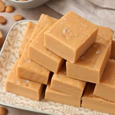 several pieces of peanut butter fudge on a plate next to peanuts and a bowl