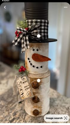 a snowman made out of tin cans on top of a counter with a tag attached to it