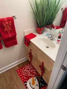 a bathroom decorated for christmas with red towels and potted plants on the counter top