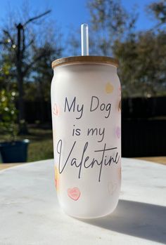 a white cup with writing on it sitting on top of a table next to trees