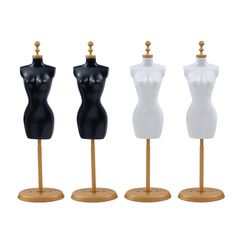 three mannequins are standing on wooden bases and one is black, the other white