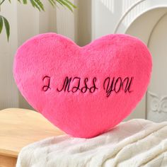 a pink heart with the words i miss you written on it sitting on a table