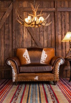 a brown leather couch sitting in front of a wooden wall with antlers on it