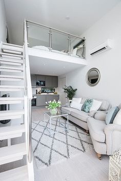 a living room filled with furniture and a staircase leading up to the second floor bedroom