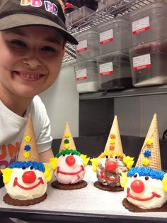 a young boy smiles in front of some ice cream cones with clown faces on them