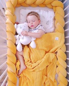 a small child laying in a crib with a stuffed animal and blanket on it