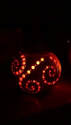 two pumpkins lit up in the dark, one with circles on it and one without