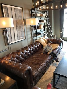 a young boy sitting on top of a brown leather couch