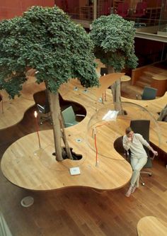 a woman sitting in an office chair next to a tree on top of a hard wood floor