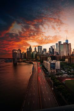 the city skyline is lit up at night with red and orange clouds in the sky