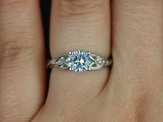 a woman's hand with a diamond ring on top of her finger and an engagement band