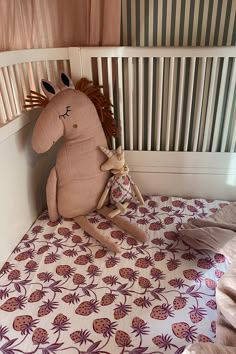 a stuffed horse sitting on top of a bed next to a wooden slatted wall