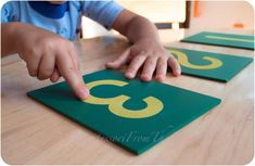 a child touching the number three on a green mat with yellow numbers in front of it