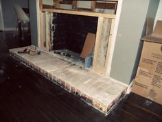 an empty fireplace in the middle of a room with boxes on the floor next to it