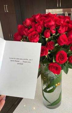 a vase filled with red roses sitting on top of a counter next to a card