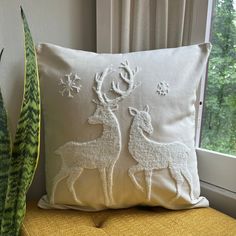 a white pillow sitting on top of a chair next to a plant