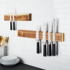 knives are hanging on the wall next to plates