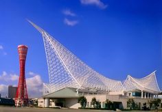 the building is shaped like an airplane and has a red tower in front of it