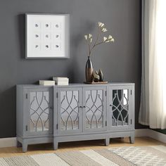 the sideboard is painted gray and has an ornate design on it, along with a vase