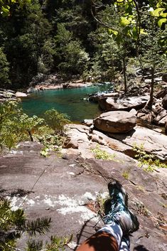 a person laying on top of a rock next to a river