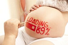 a pregnant woman has her belly painted red with the words loading 789 on it