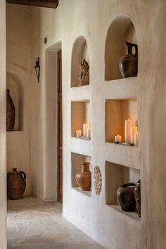 candles are lit on the shelves in an adobe - style room with white walls and stone arches