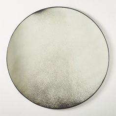 a round mirror sitting on top of a white wall next to a black and silver object