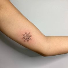 a woman's arm with a small sun tattoo on the left side of her arm