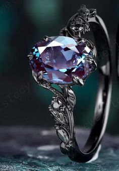 an engagement ring with a purple stone in the center and vines on it's sides