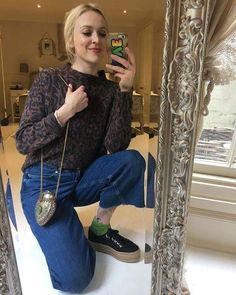 a woman sitting on the floor taking a selfie in front of a mirror with her cell phone