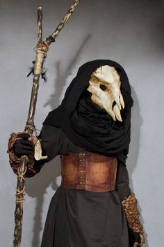 a man dressed up as a demon holding a stick and wearing a mask with an animal's head on it