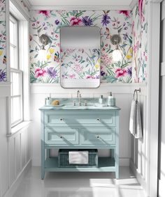 a bathroom with floral wallpaper and pink vanity, gold faucet, mirror and rug