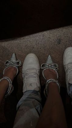 two people standing next to each other wearing white shoes with silver bows on their ankles