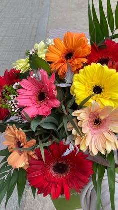 a vase filled with lots of different colored flowers