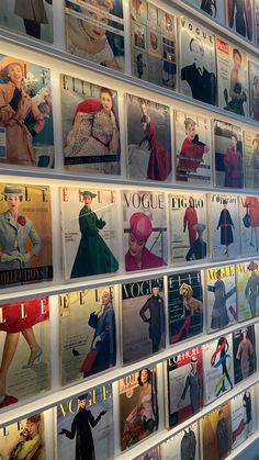 a wall covered in magazines and pictures of women's fashions on display at a store