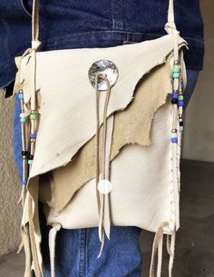 a person holding a white purse with fringes and beads on it's side